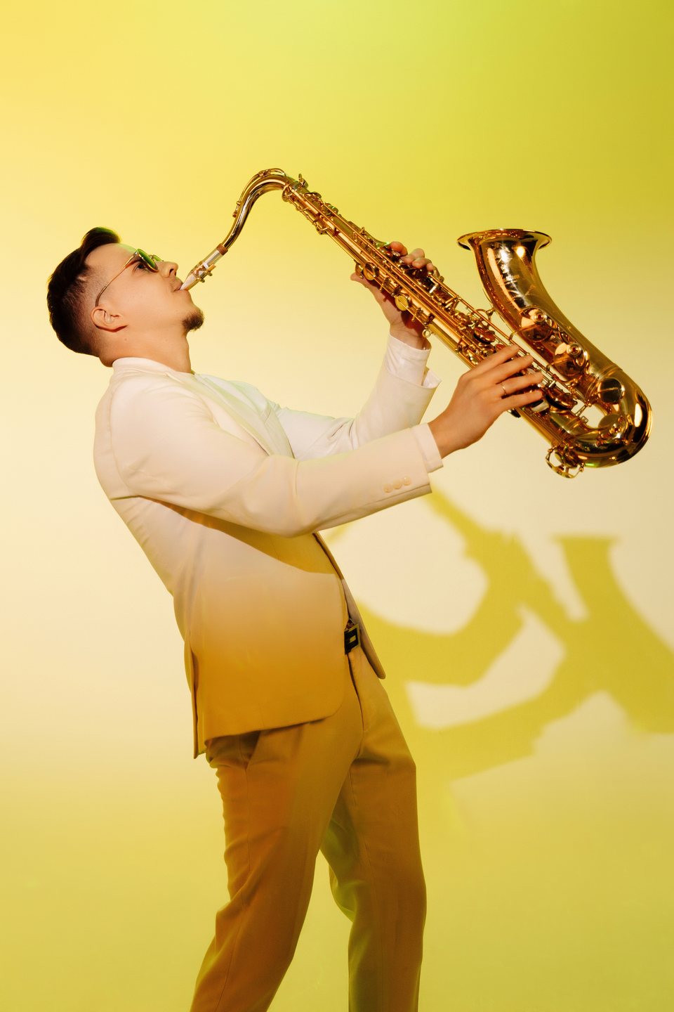 Stereo Sax играет на тенор-саксофоне в жёлтом студийном свете